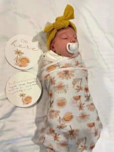 Newborn baby wrapped in blanket with dummy in mouth