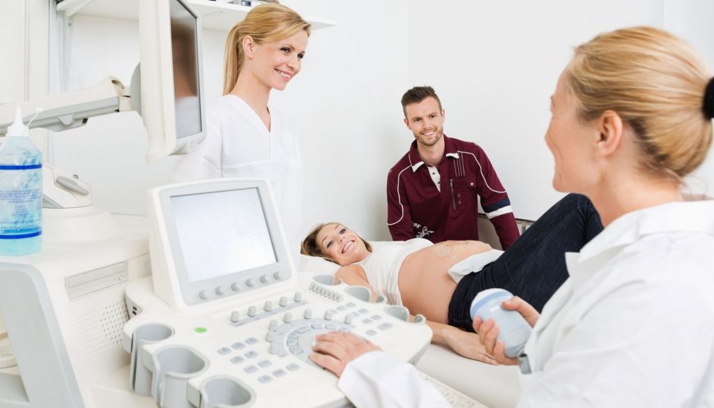 Gynecologists And Expectant Couple In Clinic