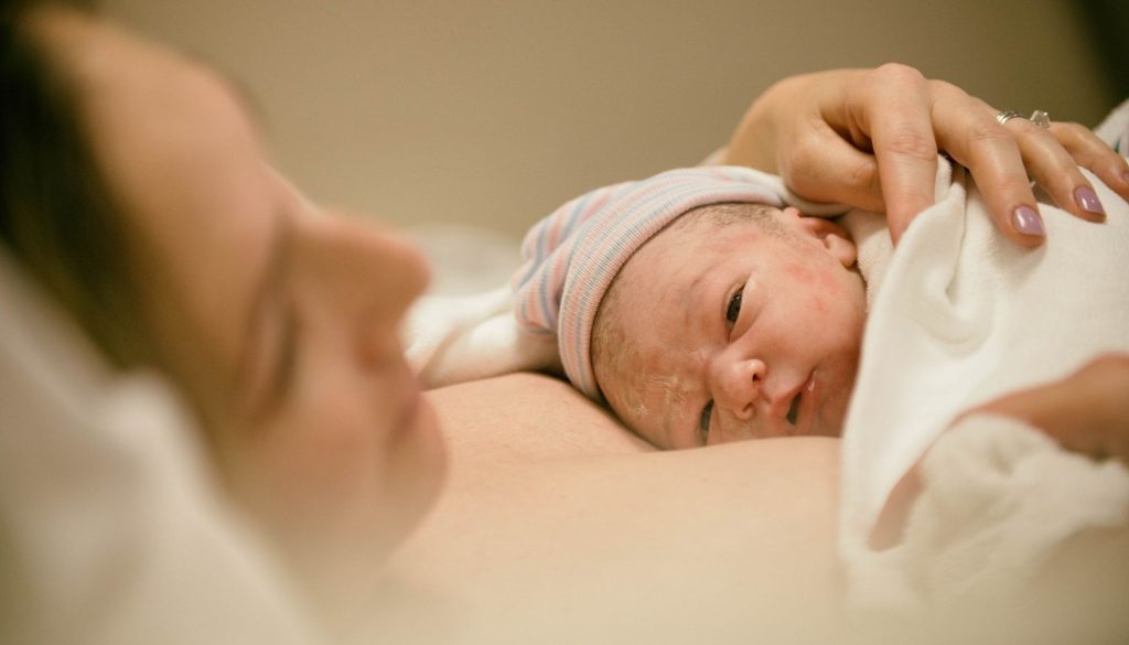 Mother holding newborn baby in white cap