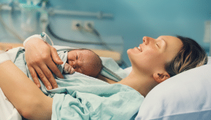 Mother and newborn. Child birth in maternity hospital. Young mom hugging her newborn baby after delivery. Woman giving birth.